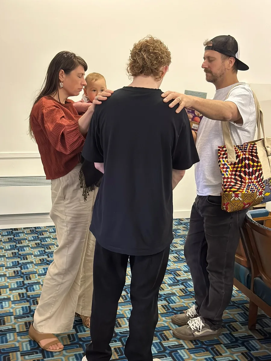 Adults praying with a young person at church